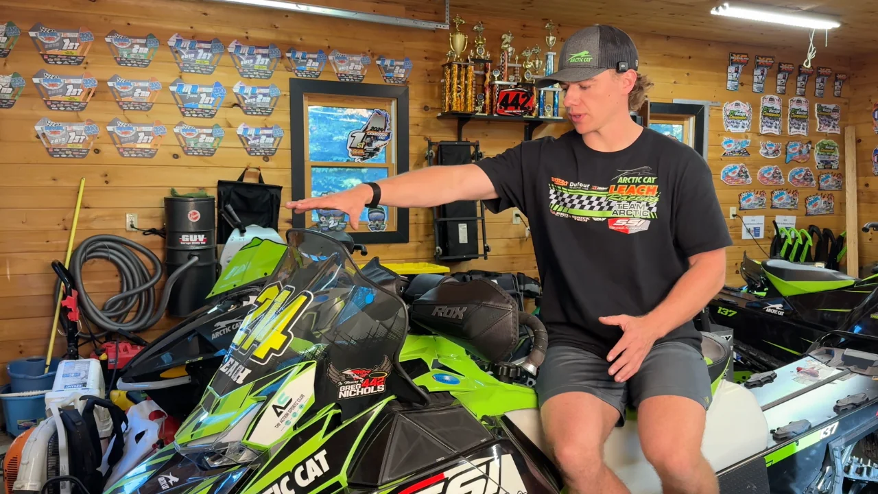 TJ Leach wearing Leach Racing apparel beside the number 214 snowmobile